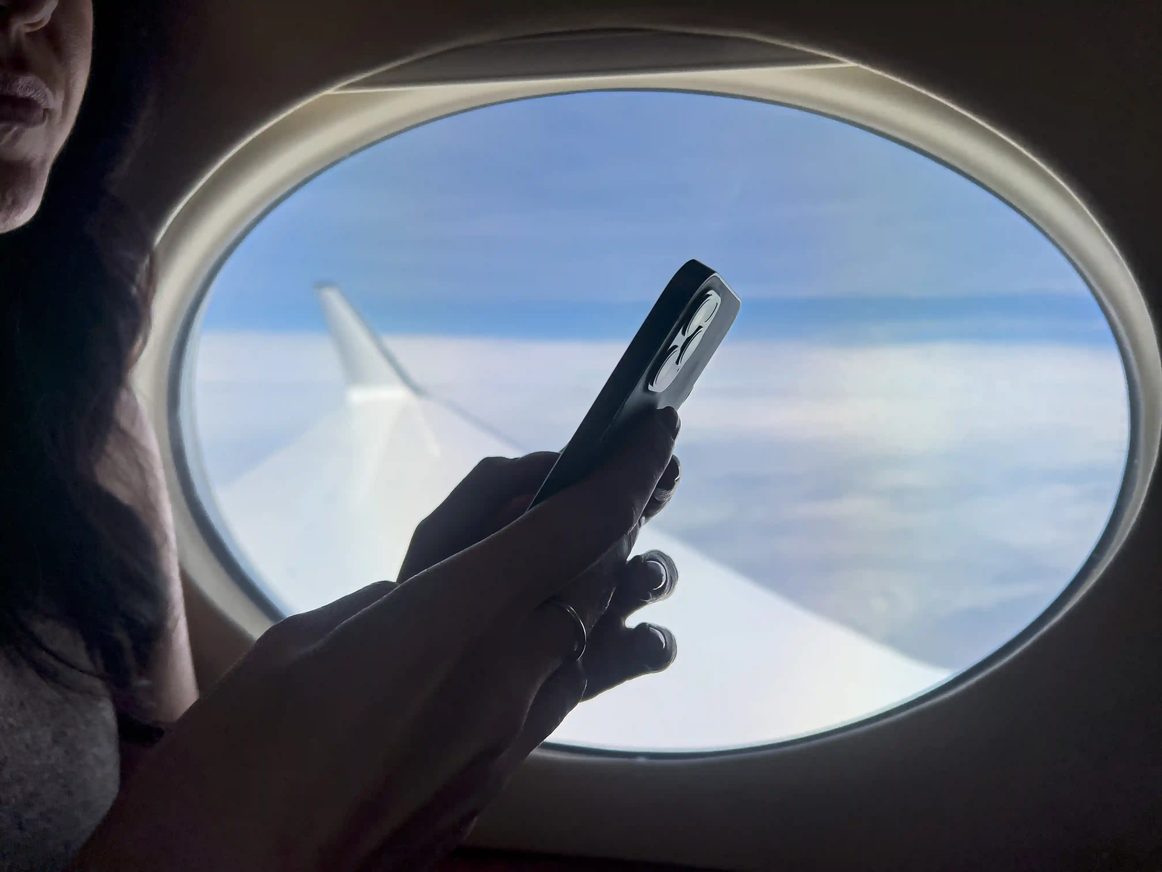 Passageiro no assento da janela de um avião usando um smartphone